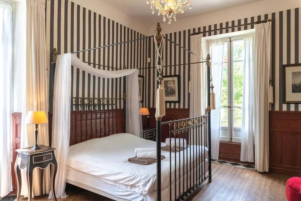 A canopy bedroom with striped wallpaper