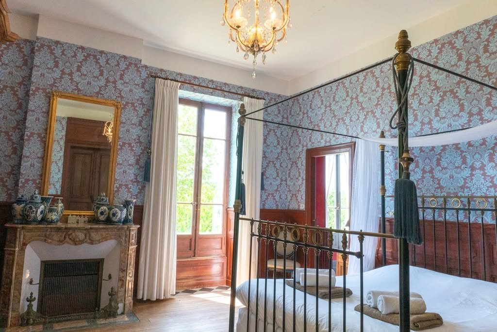 A four-poster bedroom with a fireplace and French windows