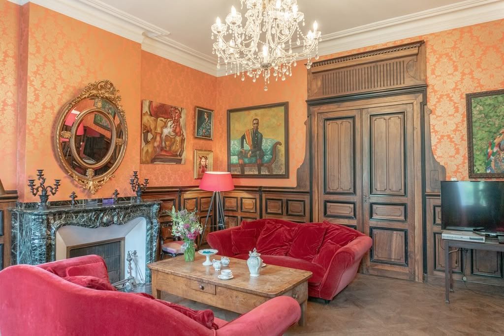 The salon with a fireplace, red sofas and a chandelier