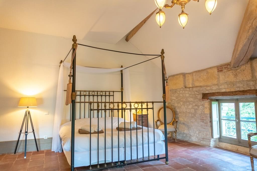 A four-poster bedroom under the beams, with exposed stone