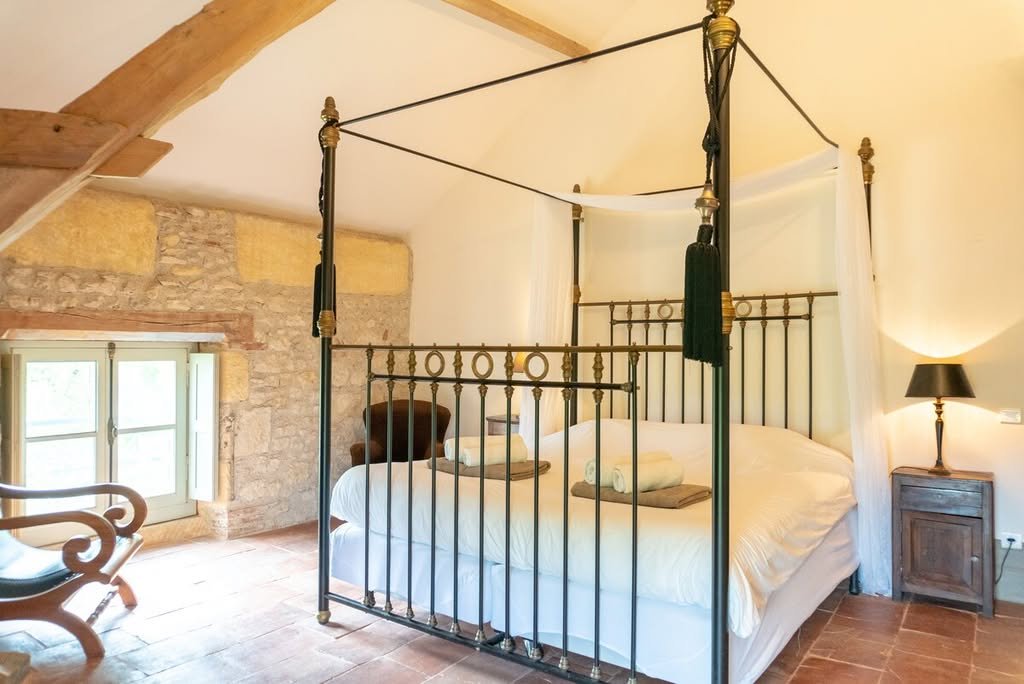 A four-poster bedroom with exposed stone