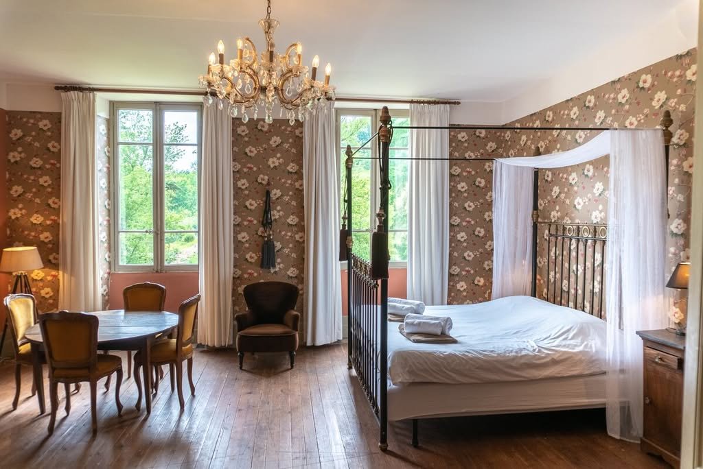 A four-poster bedroom with a chandelier and a small sitting area