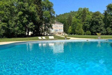 Heated swimming pool with the château behind it at Château des Pyrénées, Ariège